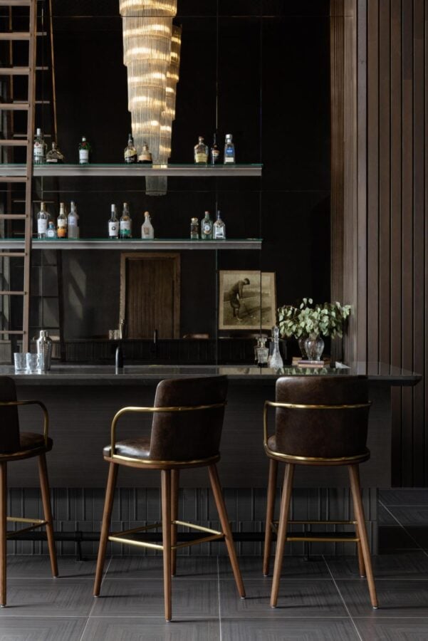 Luxury commercial bar lounge featuring custom bar stools, dark wood millwork, illuminated shelving, and hospitality-inspired interior design for multifamily amenities.